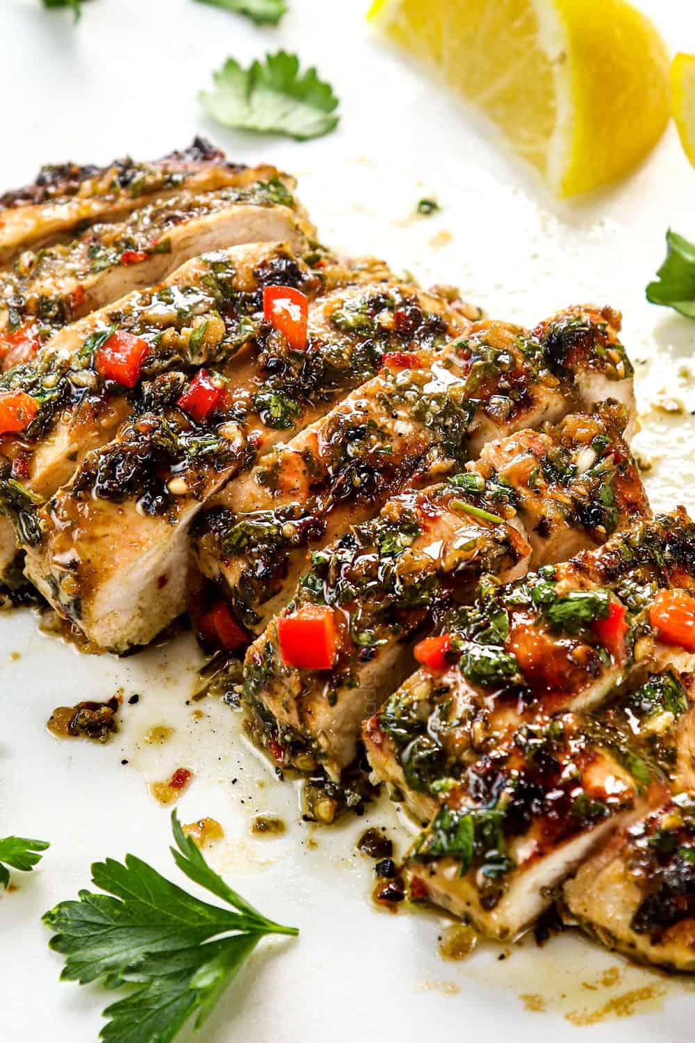 Close up of a delicious grilled chicken breast with chimichurri sauce, garnished with lime wedges