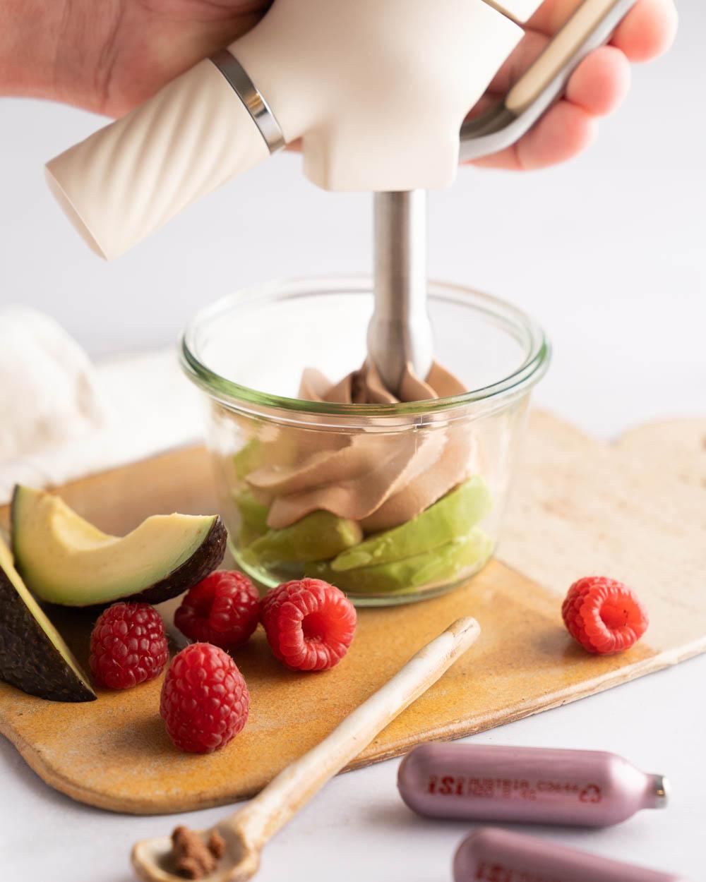 Close-up shot of hands carefully pouring chocolate into the avocado mixture