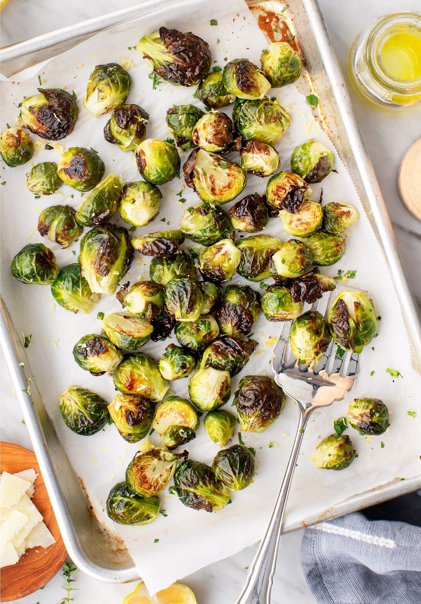 sheet pan of roasted Brussels sprouts with lemon slices and fresh herbs