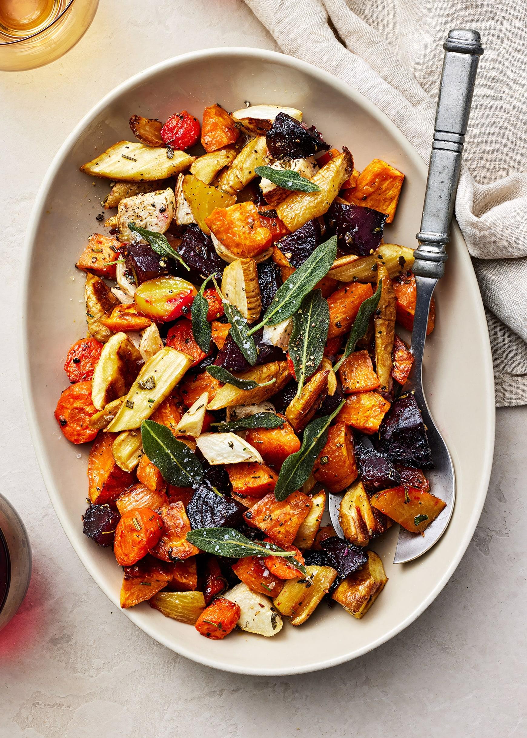 Close-up of a vibrant mix of roasted root vegetables—carrots, potatoes, and parsnips—in a rustic bowl, with herbs sprinkled on top.