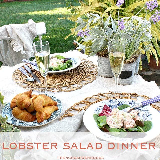 A beautifully styled table setting with two lobster rolls and a celery salad