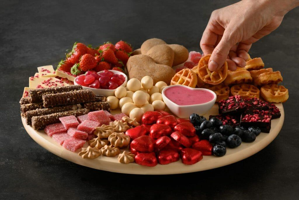 A variety of dippers, such as graham crackers, shortbread cookies, and toasted baguette slices, arranged around a bowl of cranberry sauce dip
