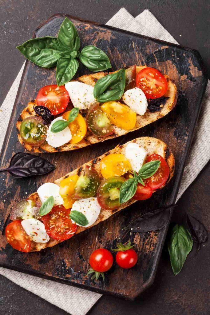 A rustic wooden board featuring a golden-brown Caprese frittata, garnished with fresh basil leaves and a drizzle of balsamic glaze