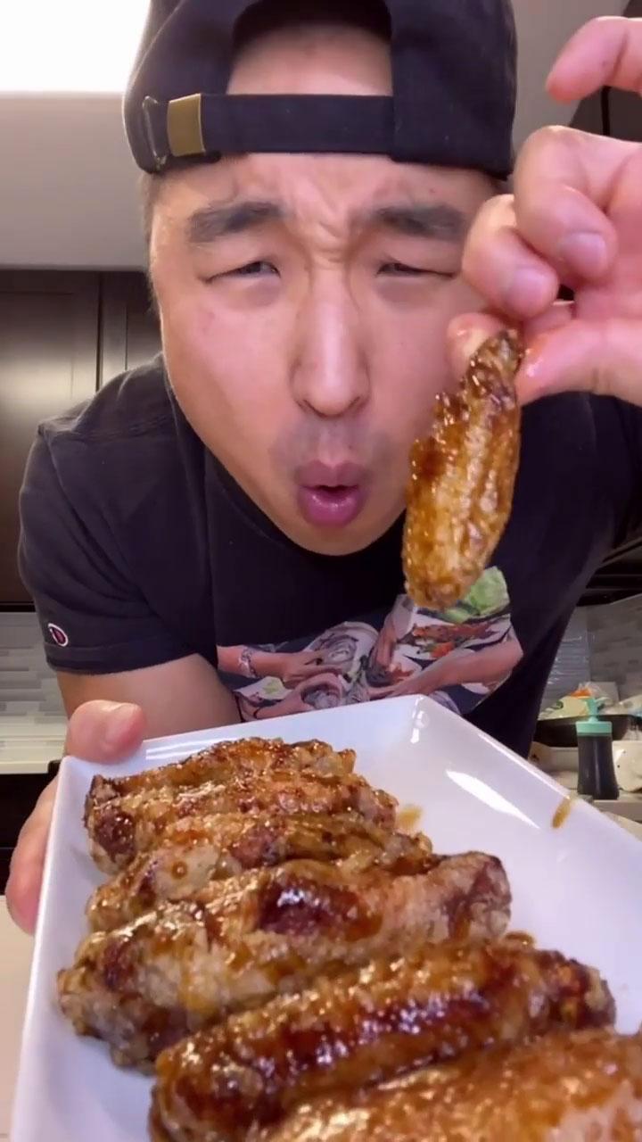A person enjoying a plate of Korean BBQ wings