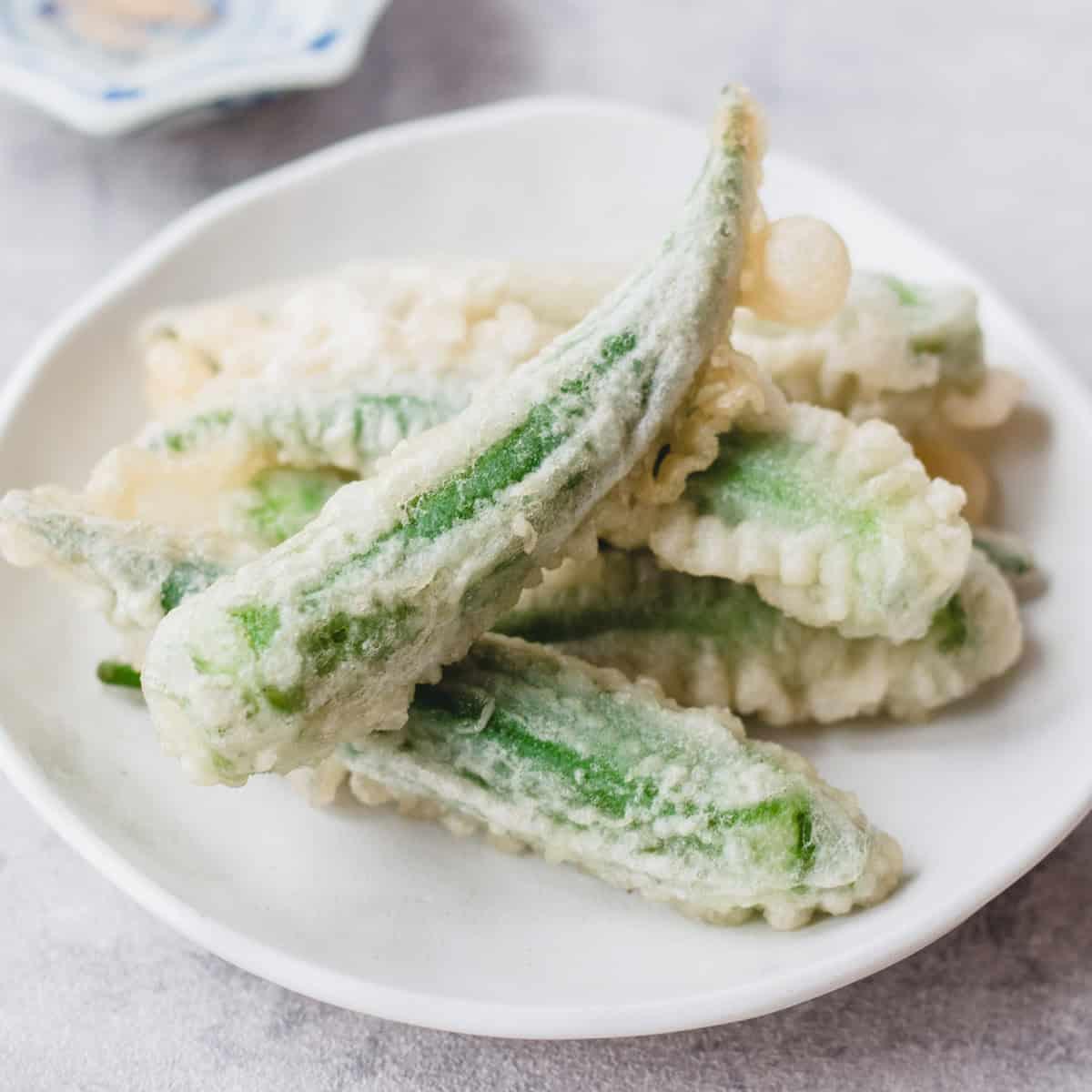 overhead shot of a plate of okra tempura with a bowl of smoked paprika mayo and a small dish of sea salt