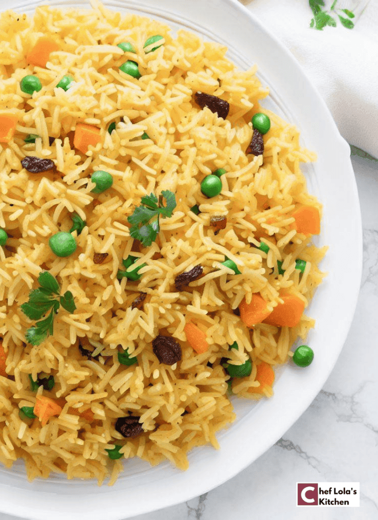 Close-up shot of a plate of fluffy boiled rice with peas and carrots, garnished with fresh herbs.