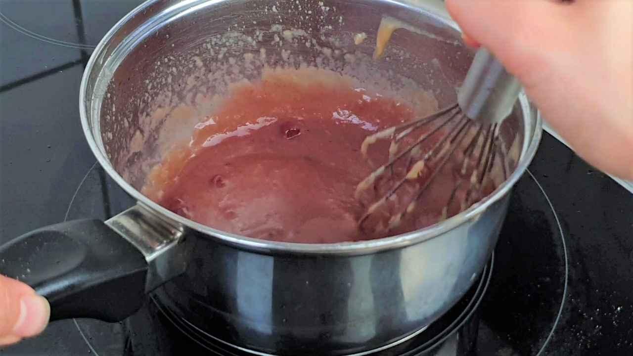 A person stirring lingonberry jam in a saucepan