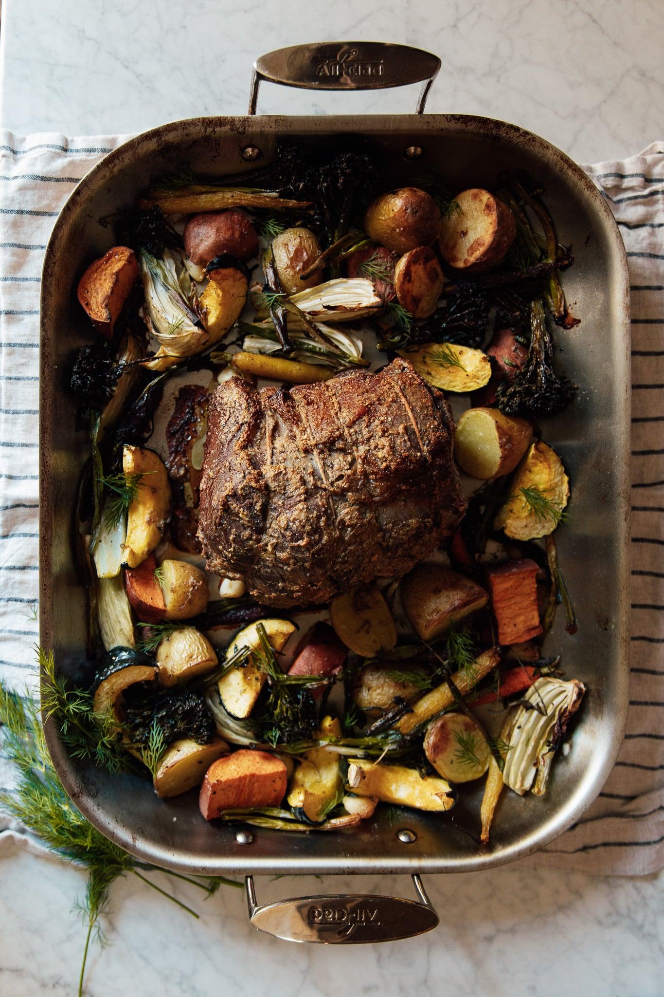 A table setting with a roasted beef roast and roasted vegetables, ready to be served