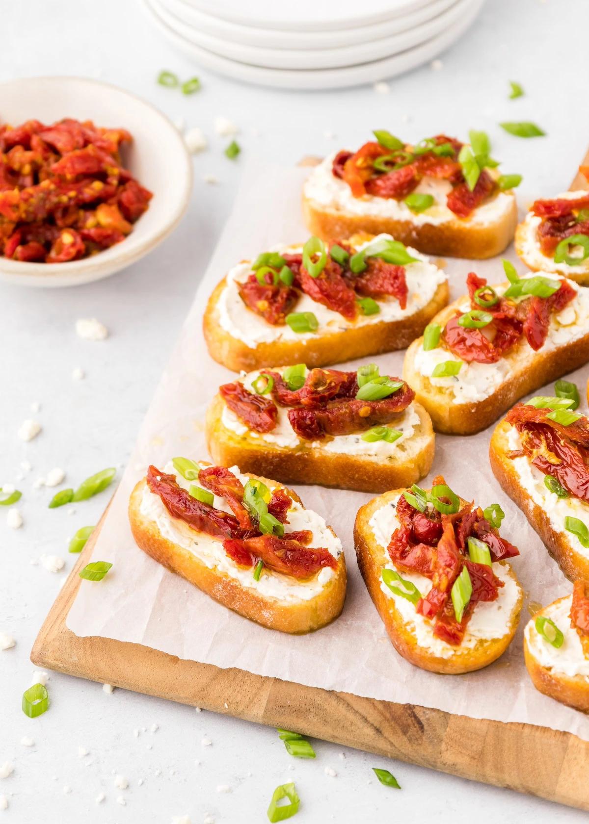 A close up of a single crostini showcasing the cashew cheese and sundried tomatoes