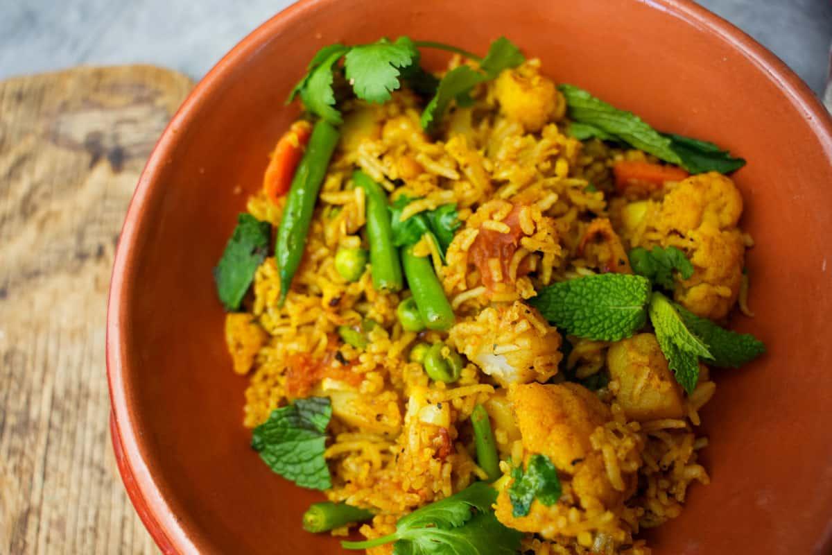 A vibrant and aromatic Green Bean & Potato Biryani, garnished with fresh cilantro and fried onions.