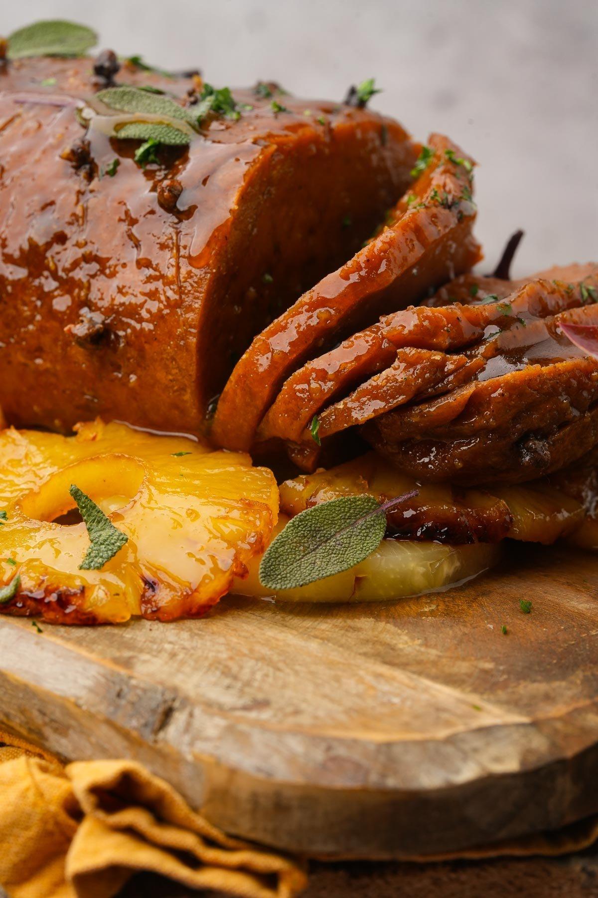 Close-up of a glazed, mustard-crusted ham with brown sugar and cloves, garnished with fresh parsley