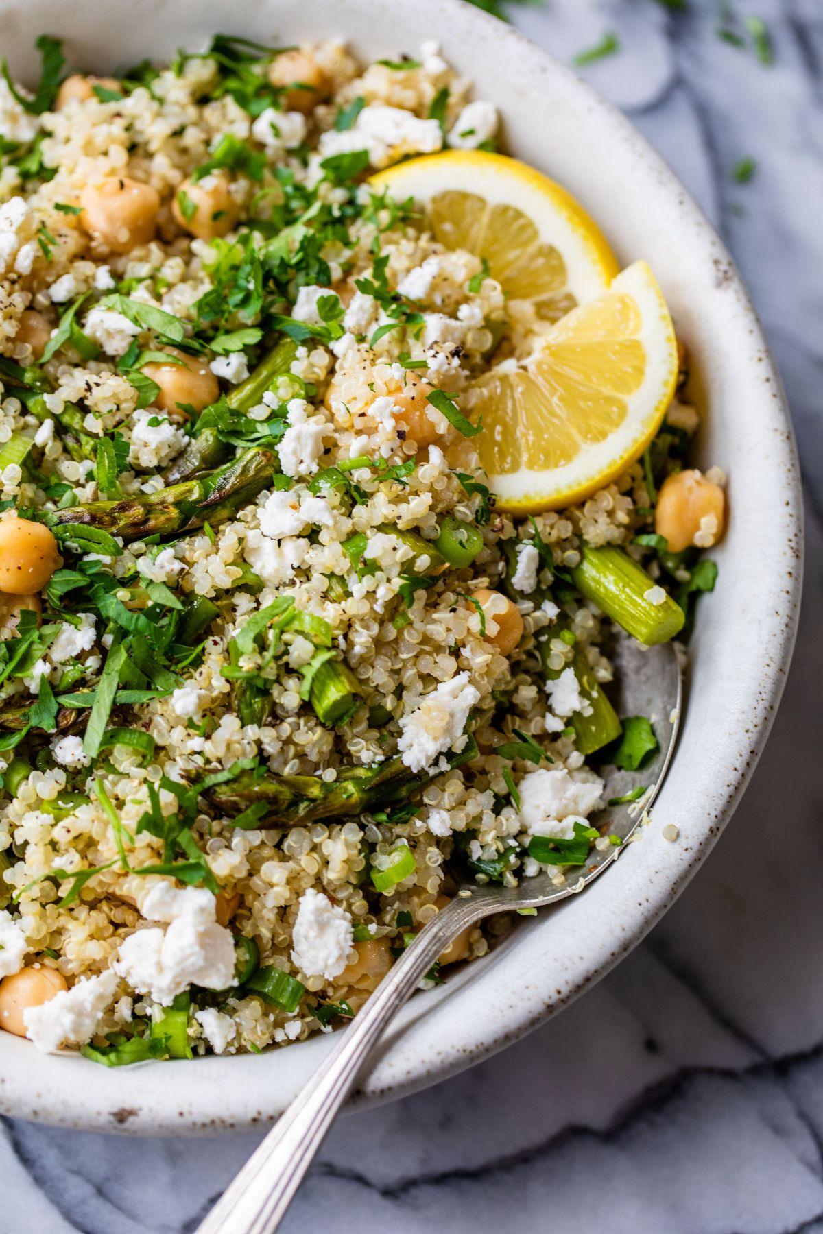 A vibrant quinoa salad with flaked salmon, blanched asparagus, and a lemon vinaigrette, garnished with fresh herbs.