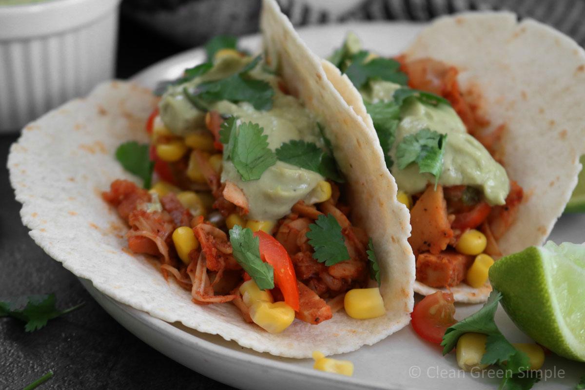 Close-up shot of delicious jackfruit tacos with a vibrant lime-cilantro salsa, garnished with fresh cilantro and lime wedges.