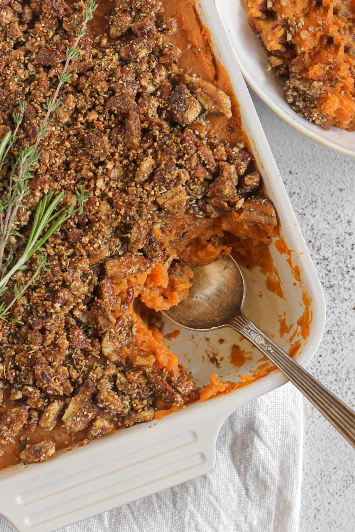 savory sweet potato casserole with fresh herbs on a rustic wooden table