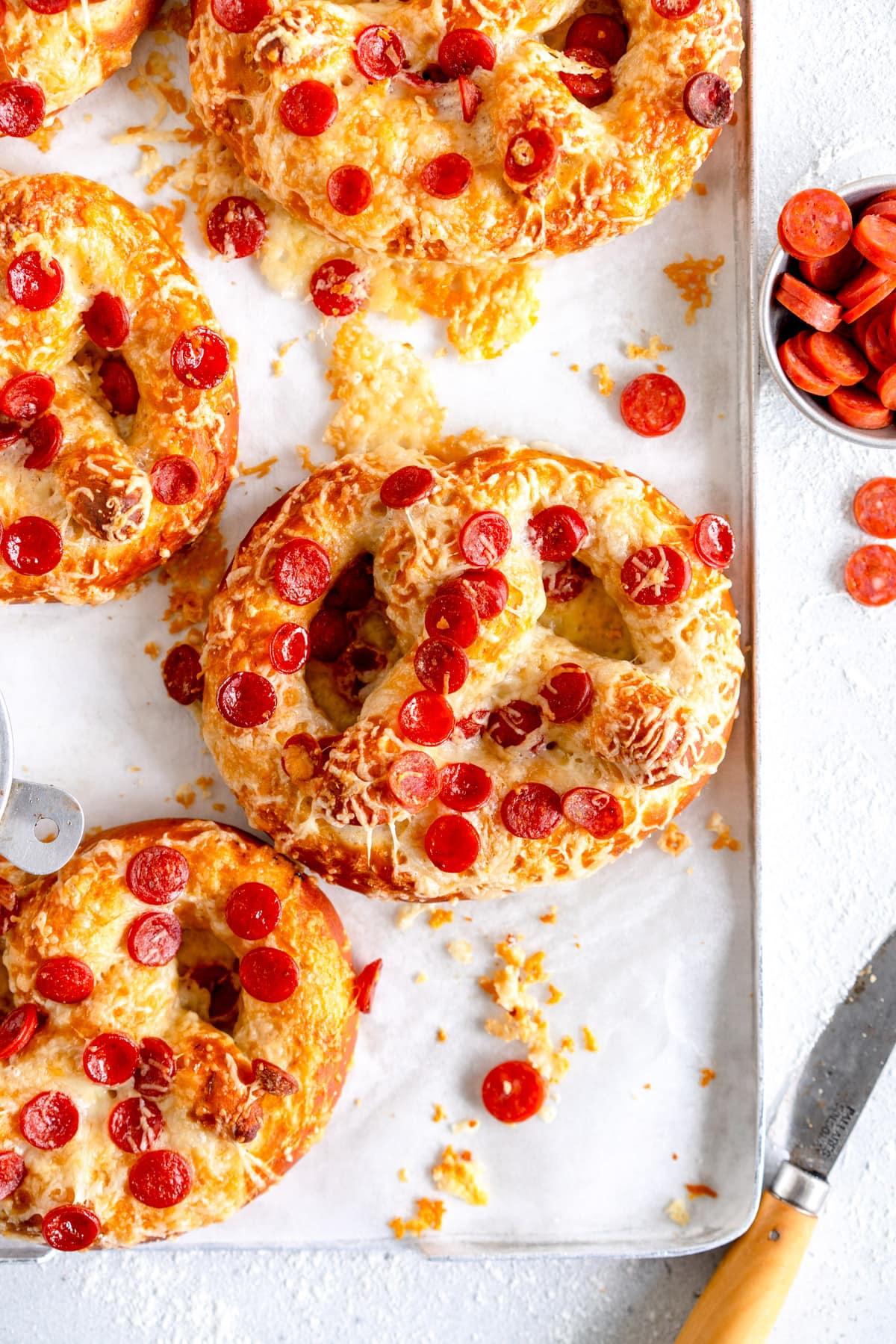 Pizza pretzels on a baking sheet with various toppings