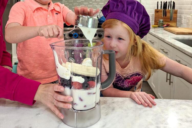 mother preparing a berry smoothie for her child