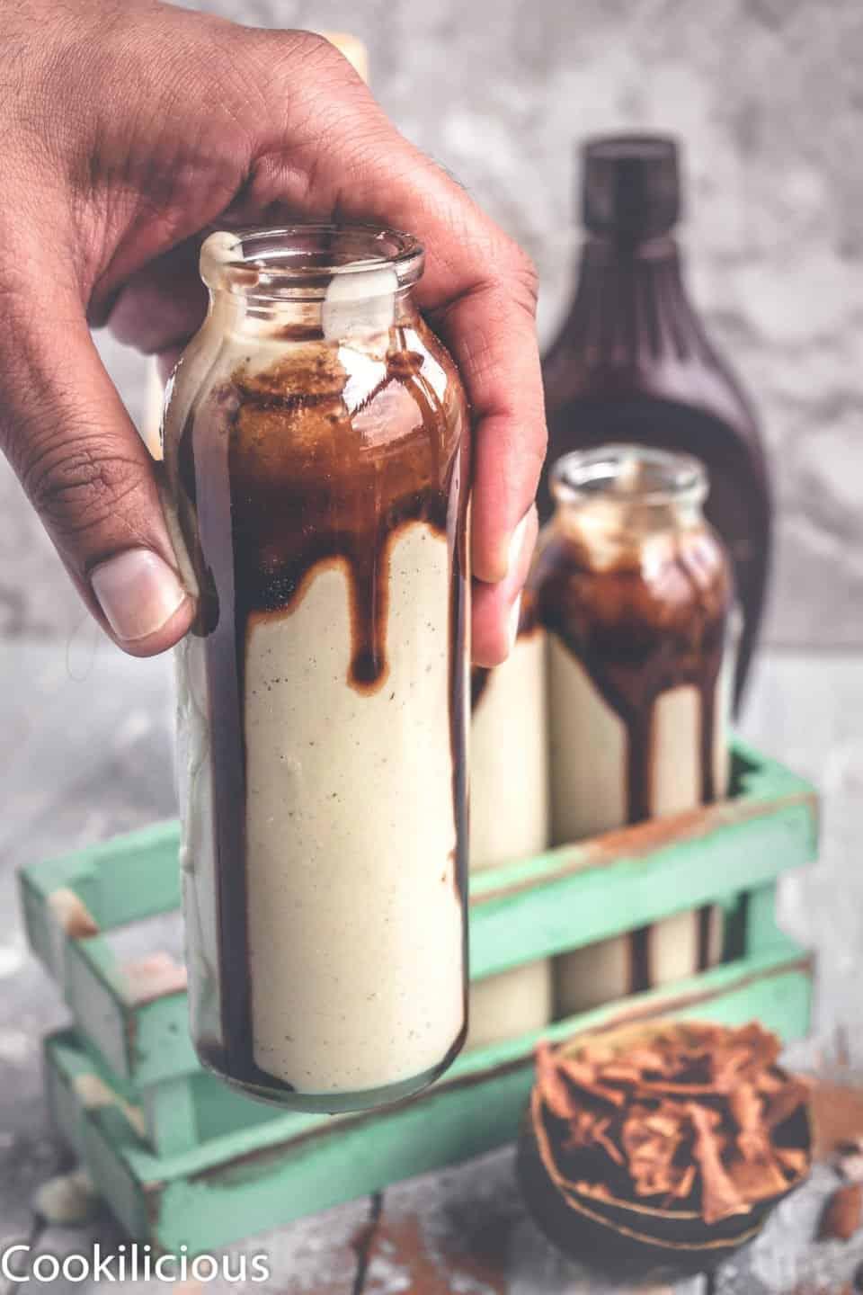 a close-up shot of the chocolate avocado smoothie being poured into a tall glass