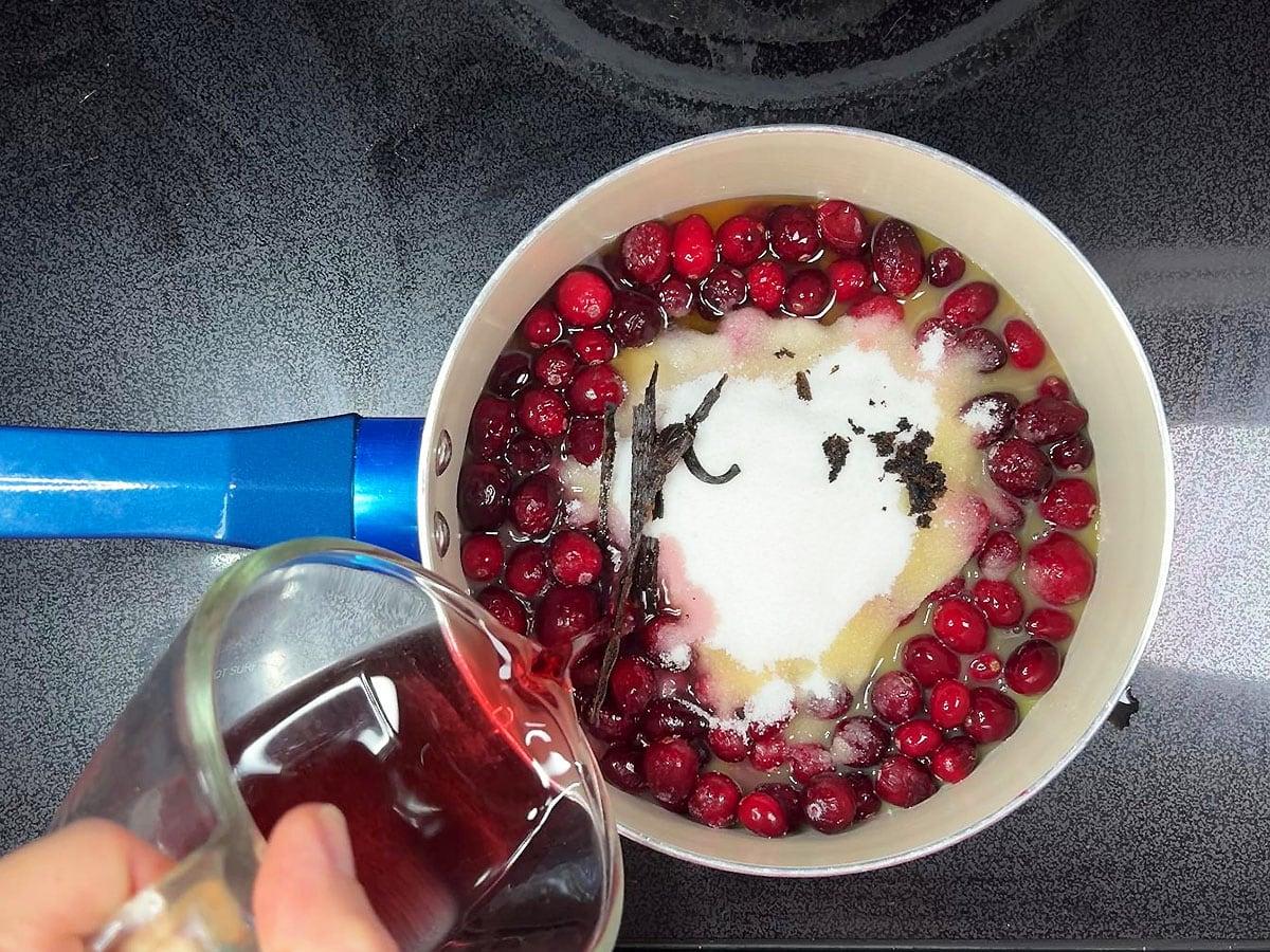 close up of fresh cranberries simmering with vanilla bean in a saucepan