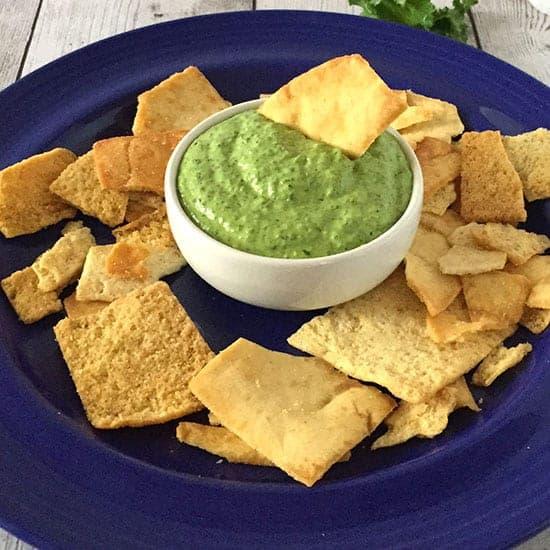 A group of friends gathered around a table, enjoying the creamy pesto dip and tortilla chips