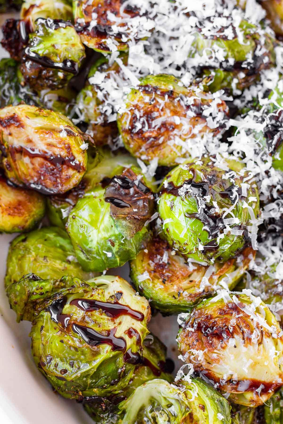 Close-up of perfectly roasted Brussels sprouts with a glossy balsamic glaze, garnished with fresh herbs