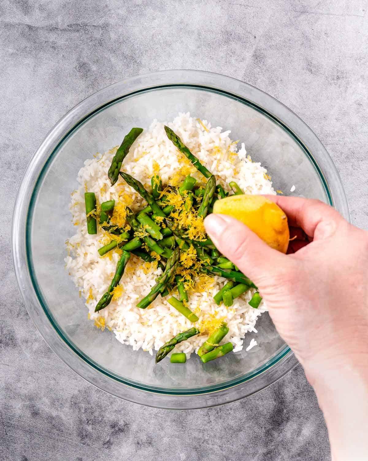 A person enjoying a bowl of steamed rice with asparagus and lemon