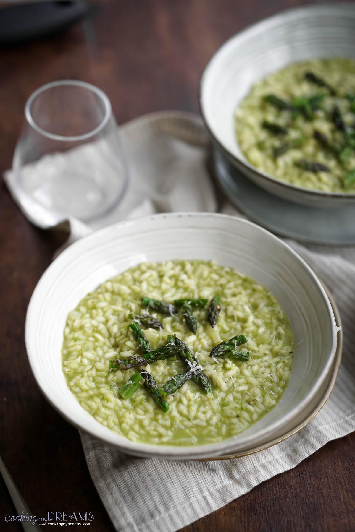 Close-up shot of a spoonful of asparagus risotto being lifted from a bowl, showcasing the creamy texture and visible asparagus pieces