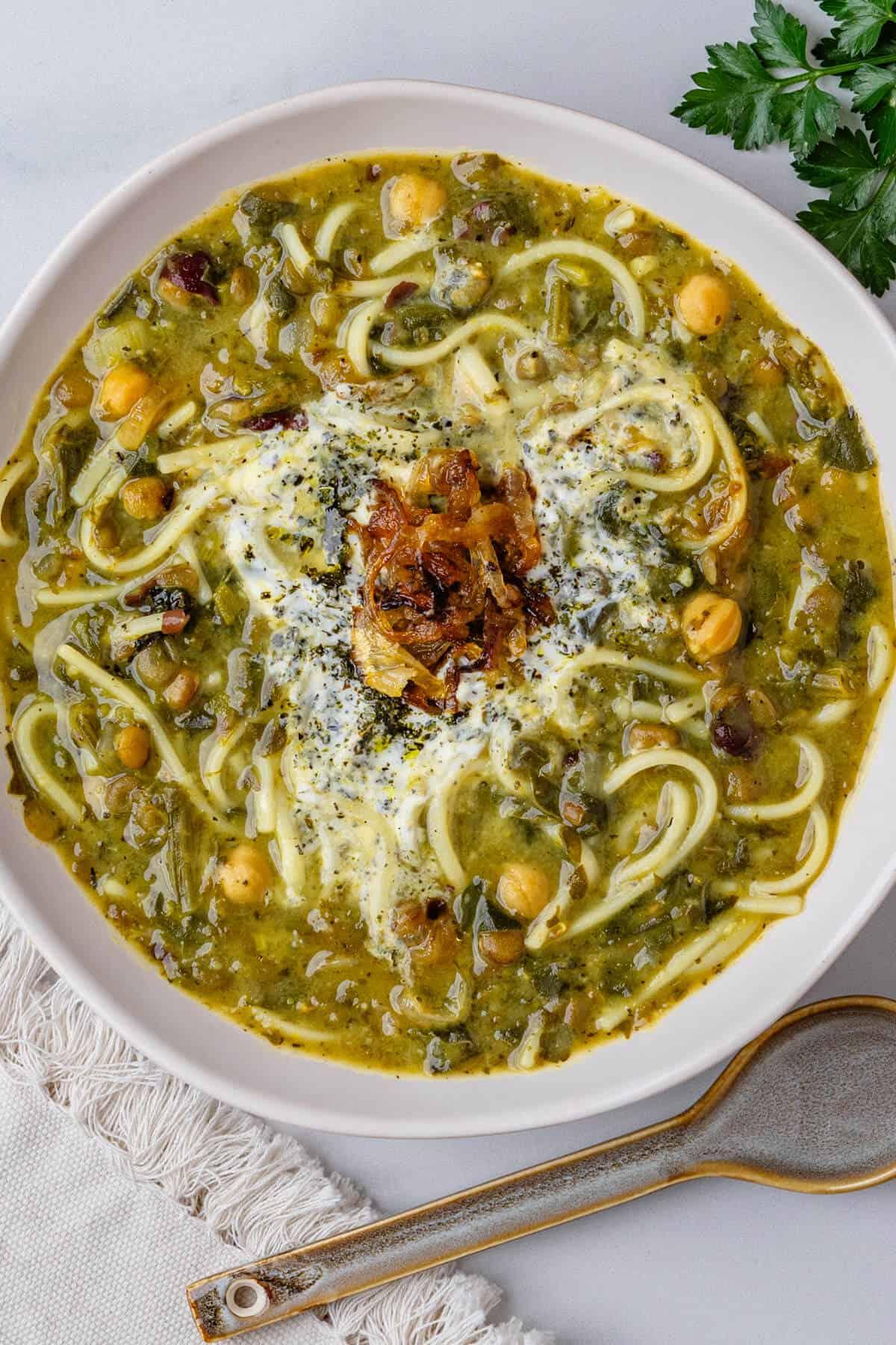 bowl of Ash Reshteh garnished with fried mint and kashk