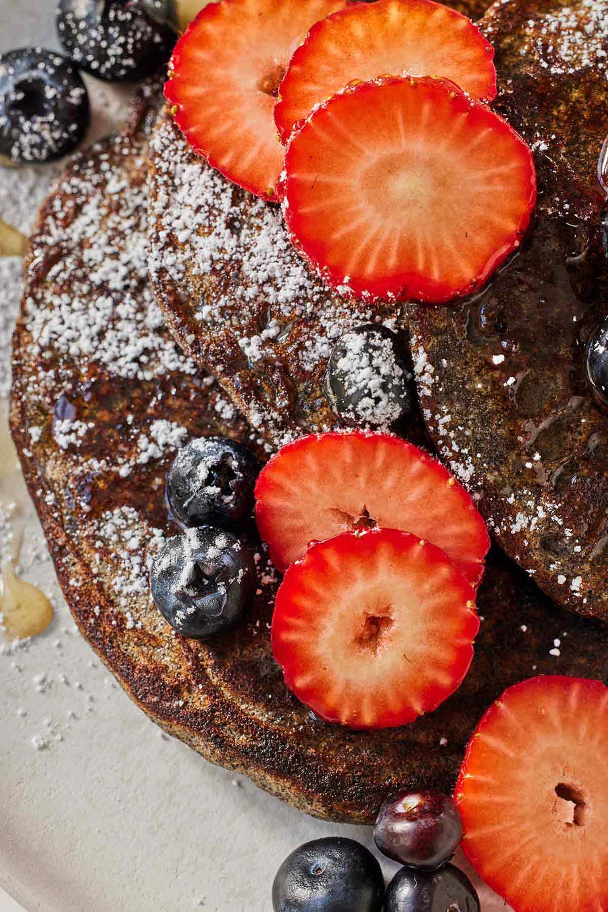 close-up shot of a buckwheat pancake with fresh berries and a dusting of powdered sugar