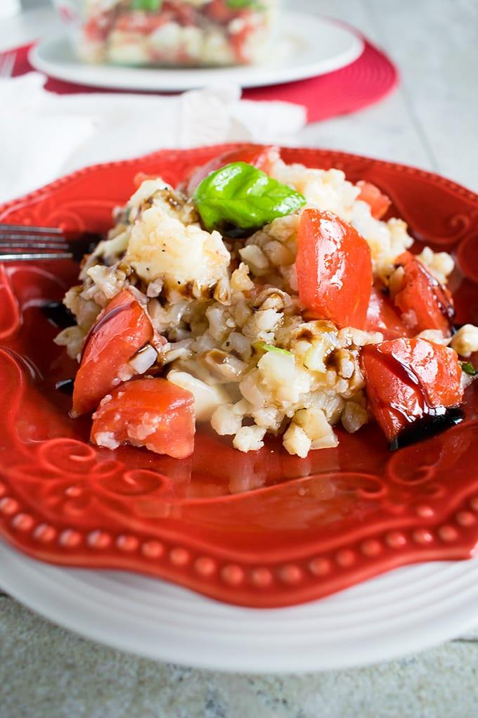 A vibrant close-up shot of cauliflower rice topped with a glistening balsamic glaze, garnished with fresh herbs.