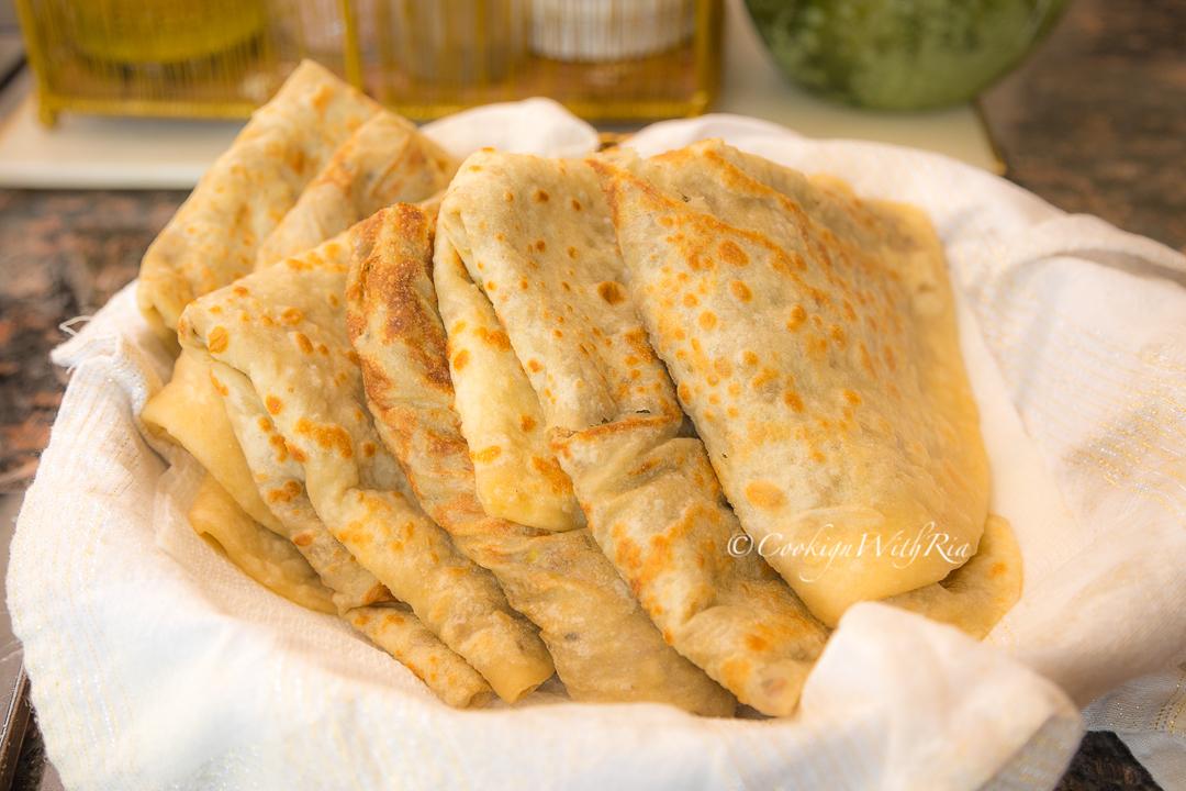 A hand breaking open a spiced lentil roti, revealing the flavorful lentil filling inside