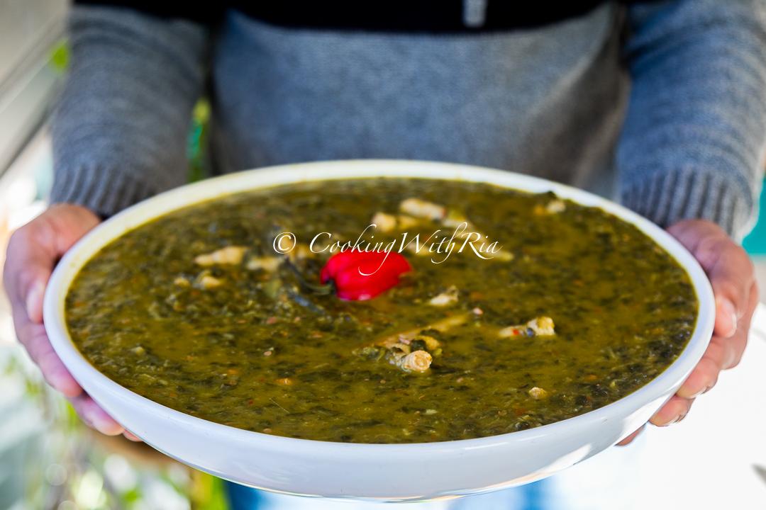 overhead shot of a pot of callaloo and watercress soup simmering on a stove