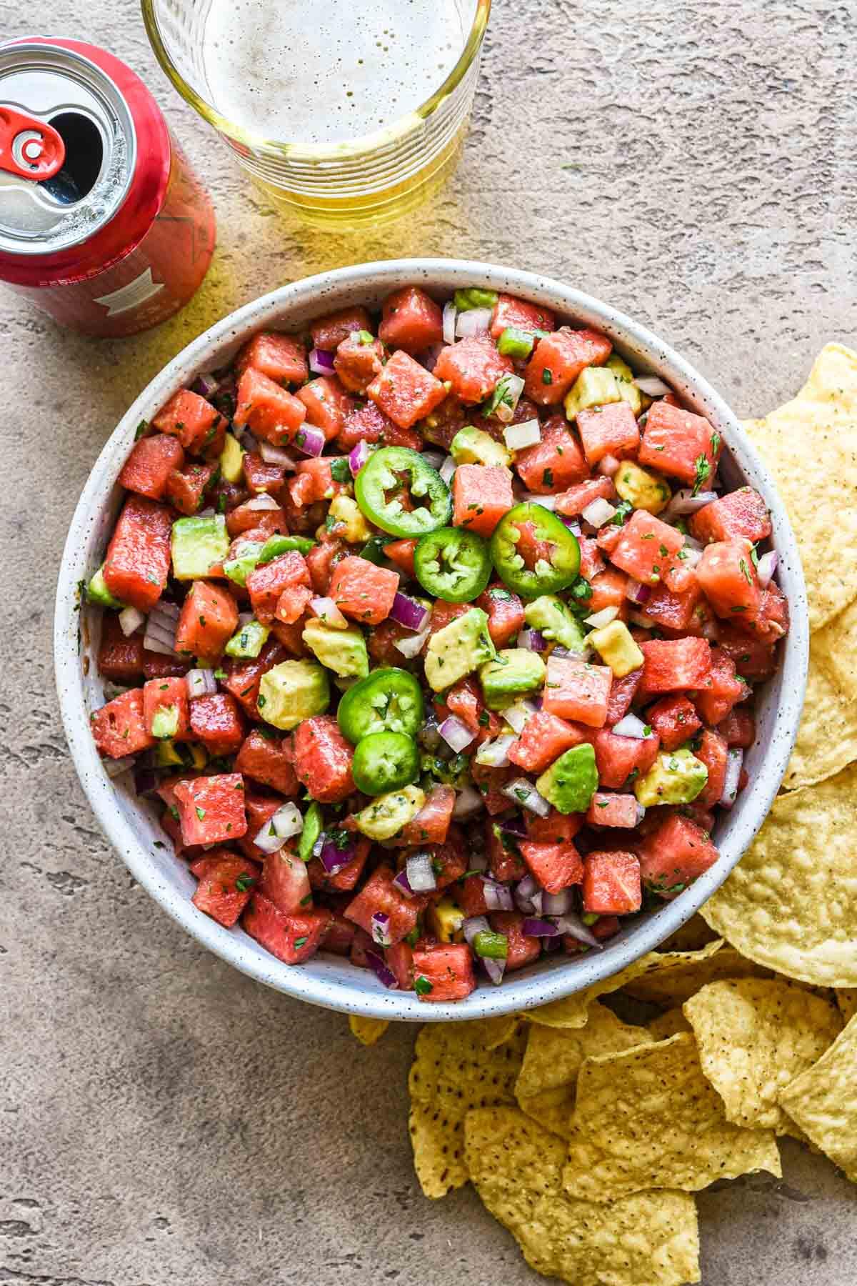 A vibrant, colorful salad with chunks of spicy watermelon, creamy avocado, and bright red jalapeños.
