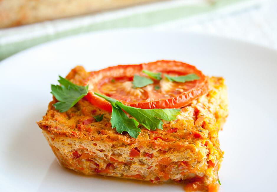 Close-up shot of a slice of tofu scramble frittata, showcasing the layers of tofu and vegetables