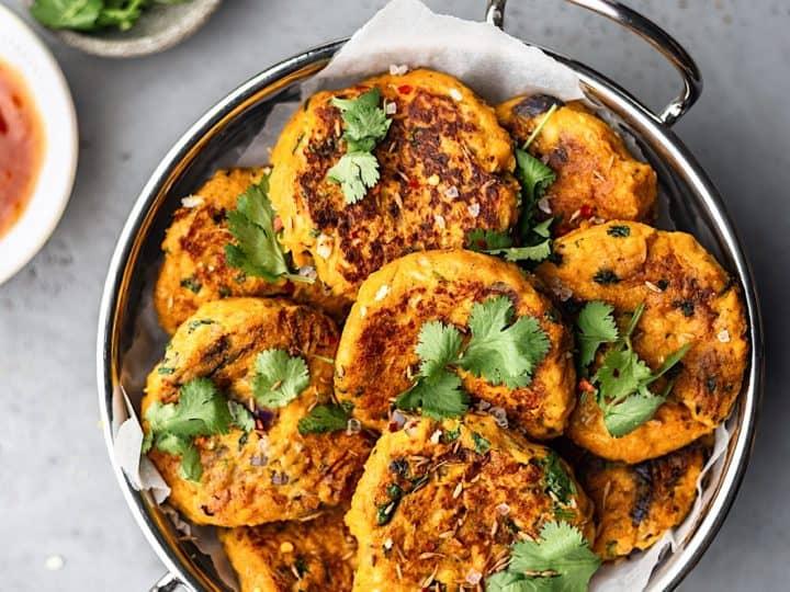 A person holding a curried sweet potato and chickpea masala burger, showcasing the layers of ingredients
