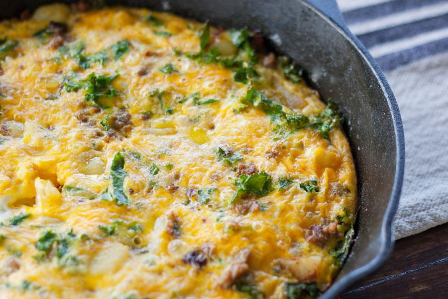 Close-up of a golden brown Kale and Sausage Frittata, steam rising.