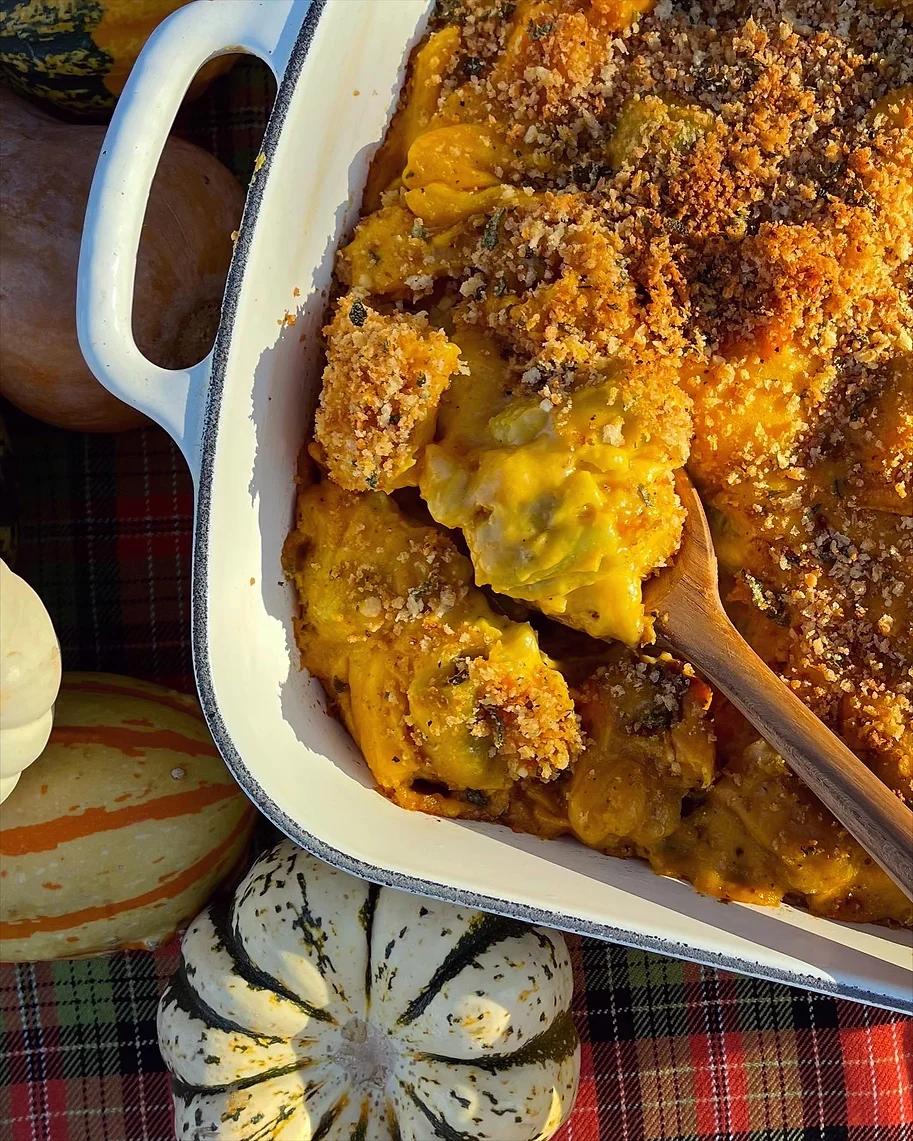 A rustic, close-up shot of a golden-brown roasted butternut squash mac and cheese, bubbling slightly in a 9x13 inch baking dish.