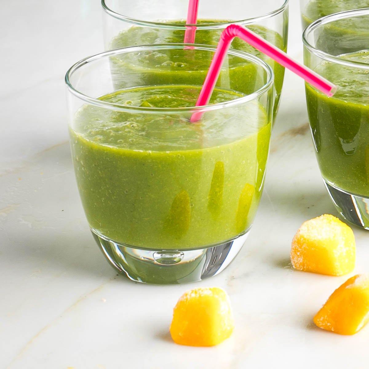 Close-up shot of a green smoothie with visible barley and mango chunks