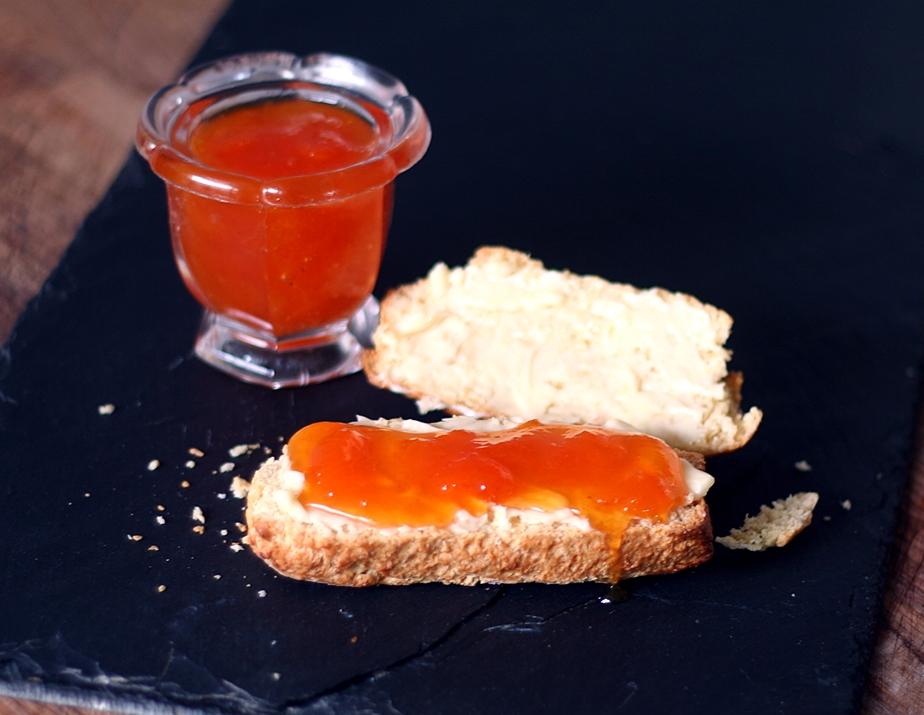 Close-up shot of a spoonful of sauerkraut and apricot jam being spread on toast