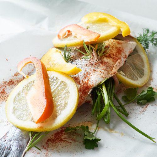 Close-up shot of the steamed sea bream being drizzled with lemon-oregano sauce