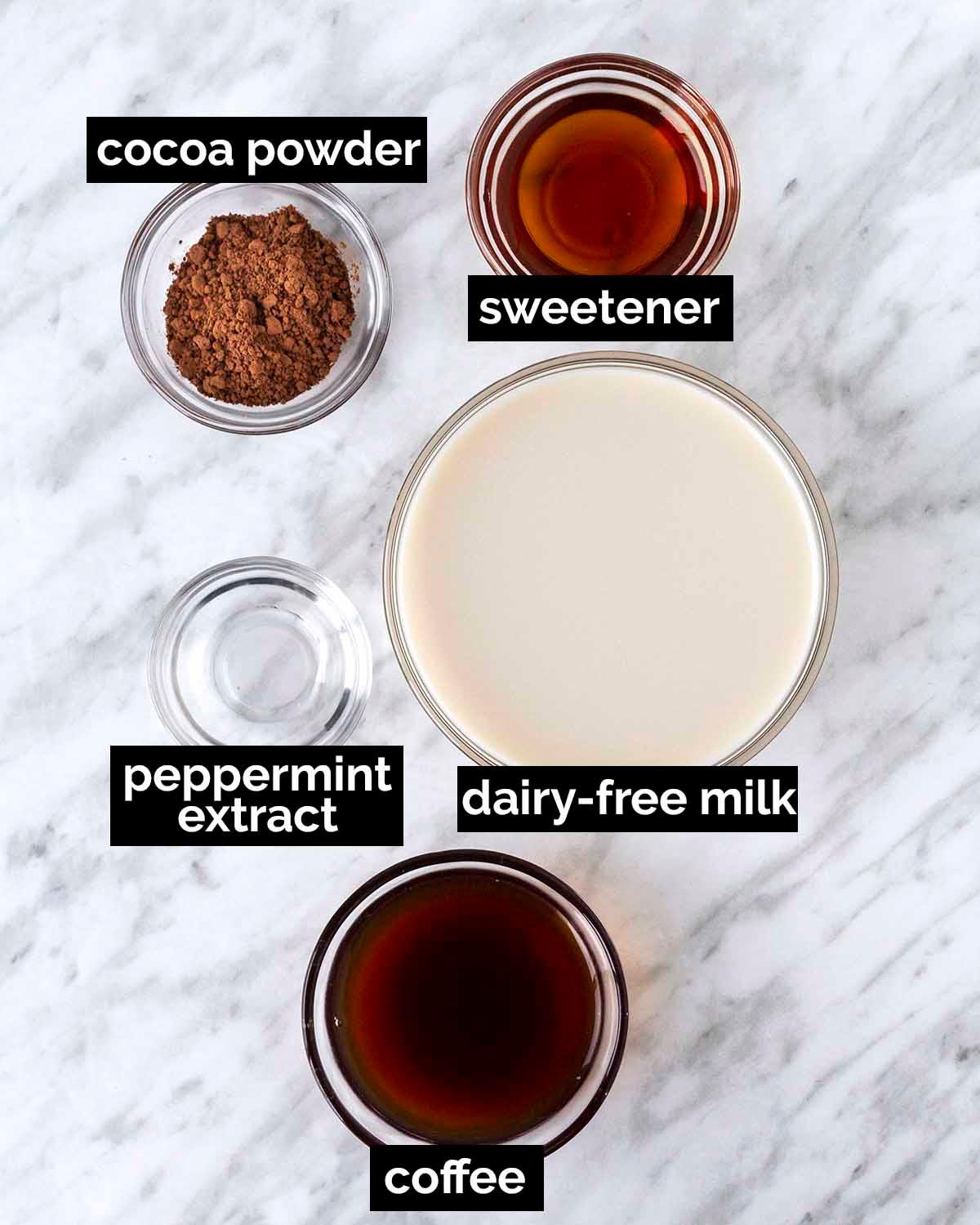 Close-up of ingredients for peppermint mocha: chocolate syrup, peppermint extract, coffee, milk