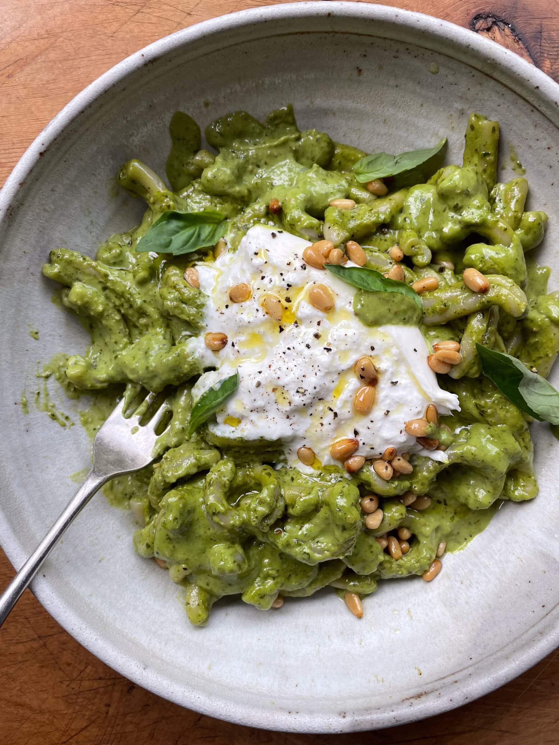 Butternut squash pasta with creamy burrata and vibrant pesto, garnished with fresh basil