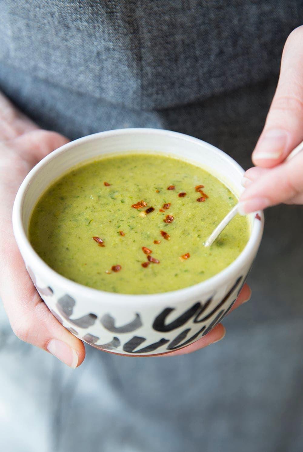 Person ladling vegan green soup into a bowl