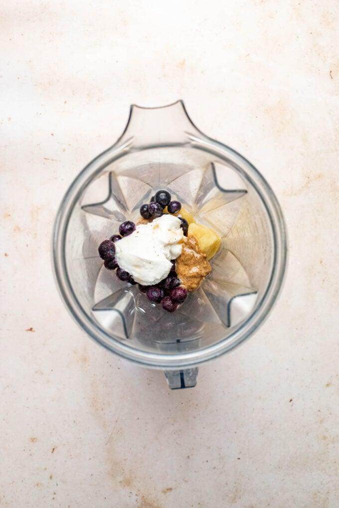 Person making a blueberry coconut cream smoothie in a blender