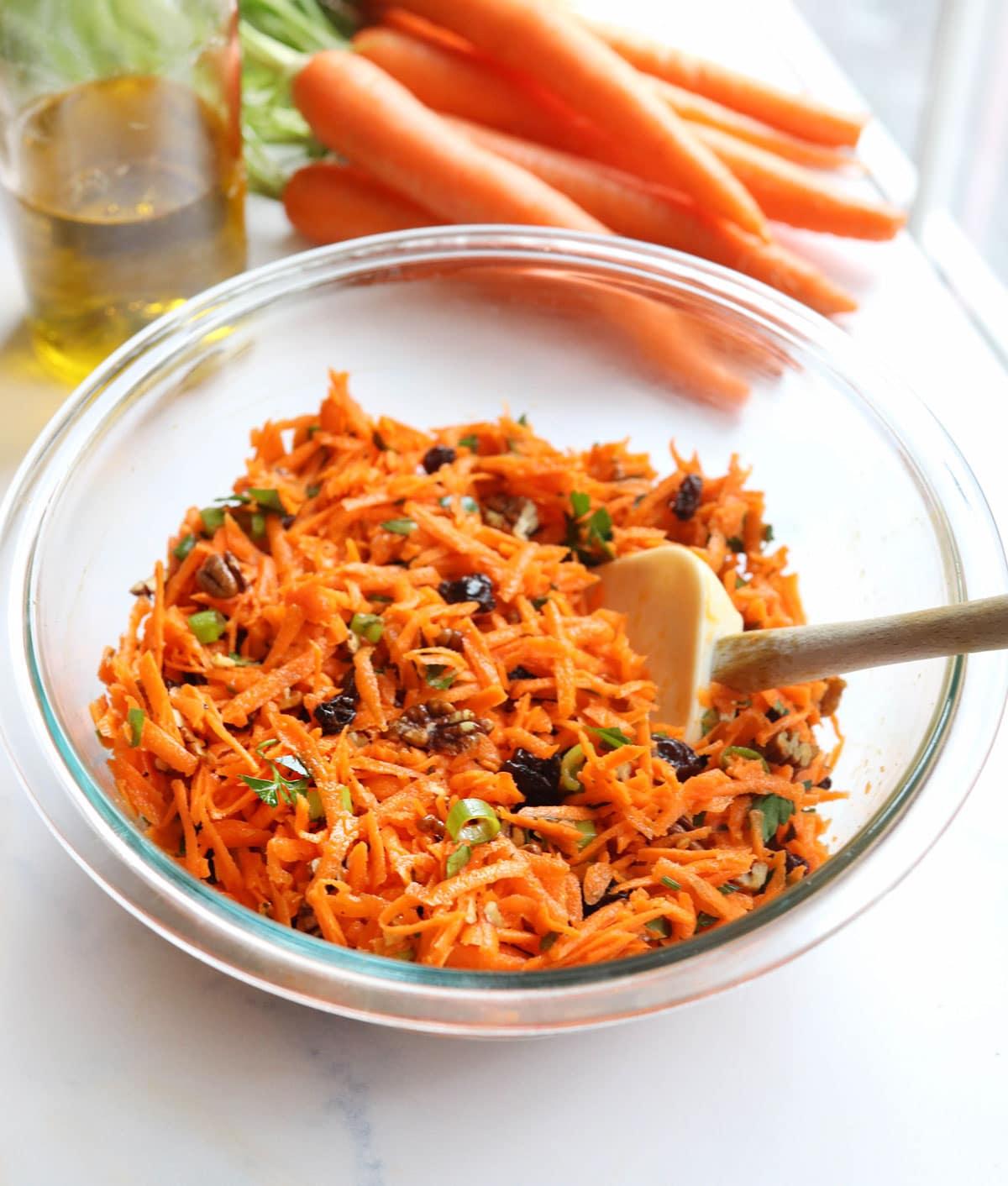 A bowl of carrot salad served alongside other dishes at a gathering