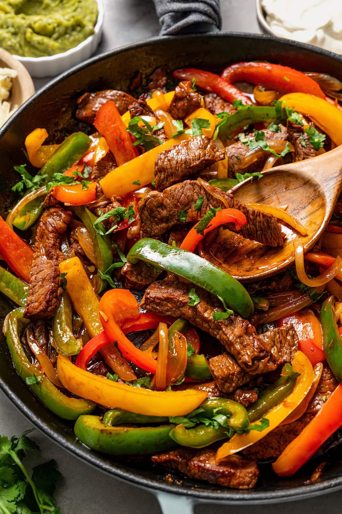 close-up of beef and bell pepper fajitas being cooked in a cast iron skillet