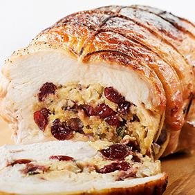 Close-up of a stuffed turkey breast being sliced, showing the goat cheese and fig filling