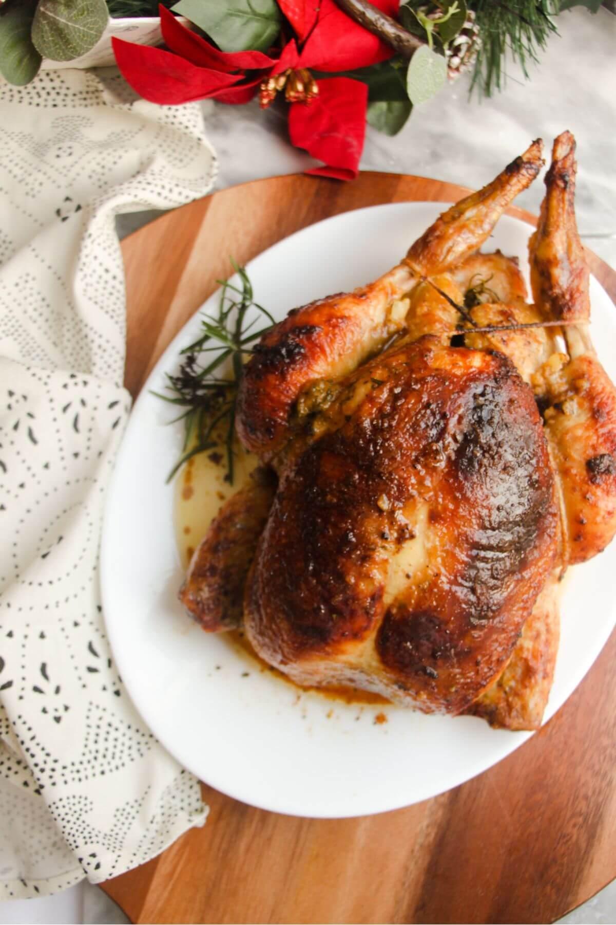 Juicy roasted chicken with a glistening barbecue sauce, surrounded by fresh herbs.