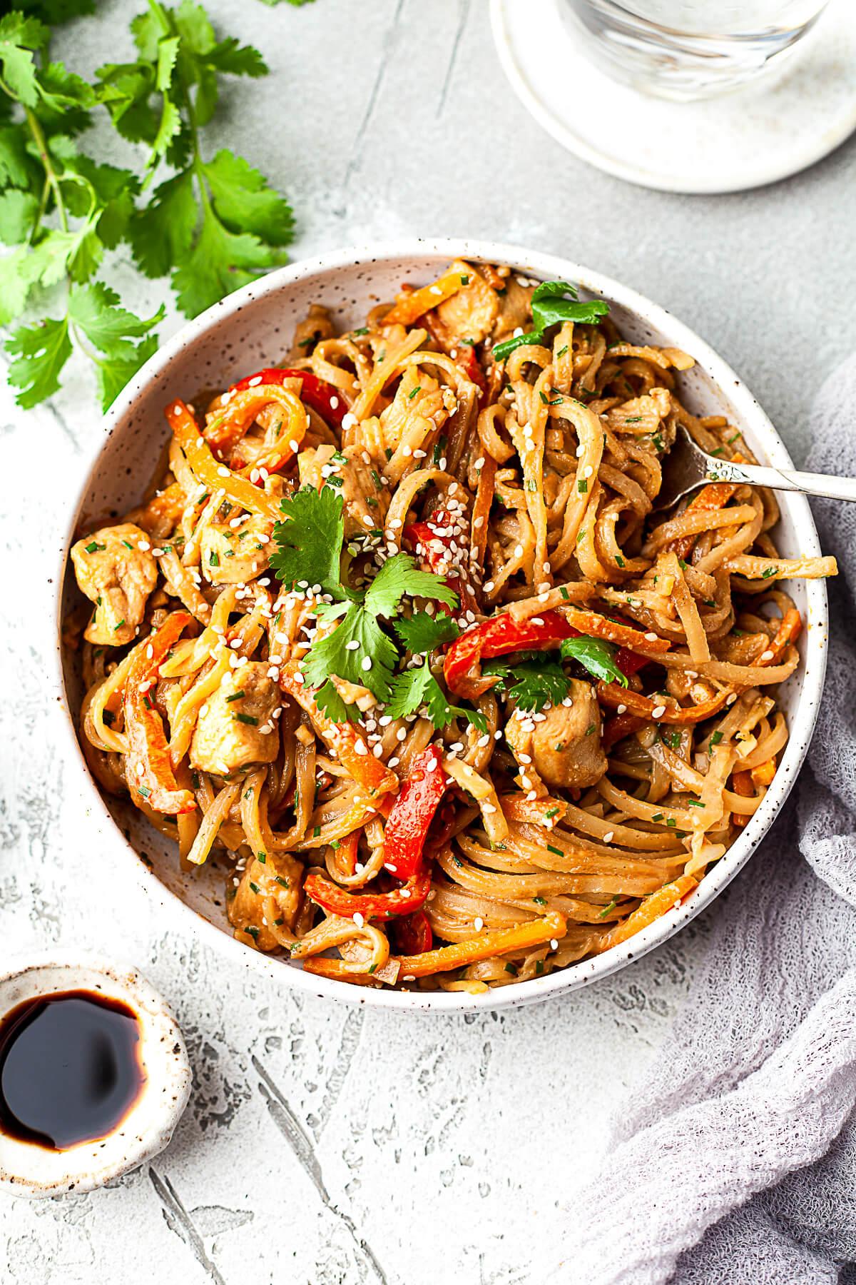 Bowl of spicy peanut sauce with sesame seeds and cilantro