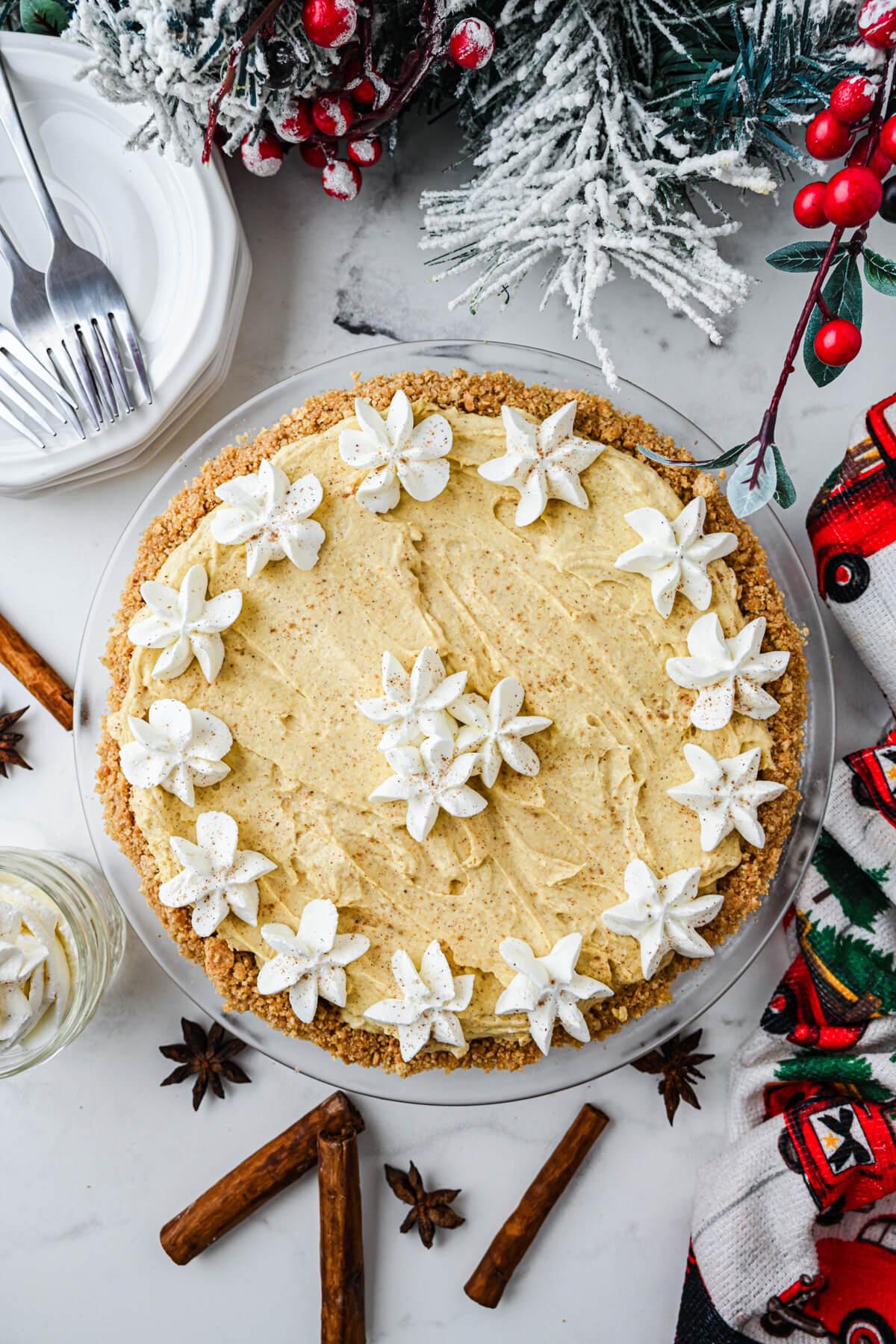 Ingredients for eggnog pie laid out on a rustic wooden table: eggs, milk, cream, sugar, nutmeg, pie crust
