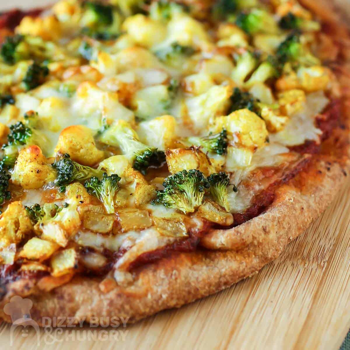 Close-up shot of a slice of Vegetable Curry Pizza with Cashew Cream, showing the creamy sauce and colorful vegetables.